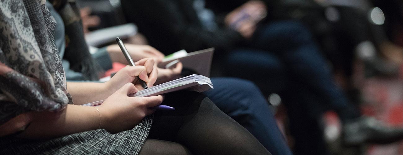 Woman writing notes during conference